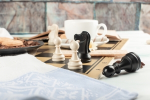 Tablero de ajedrez y tasa de café sobre una mesa representando estrategias para vender tu casa bien y en poco tiempo